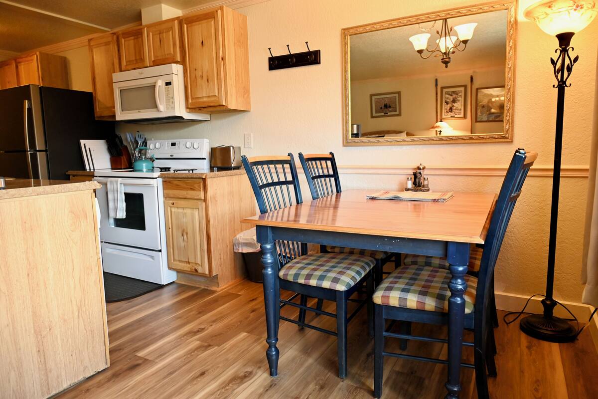 A kitchen with wooden cabinets, a microwave, a stove, and a dining table with chairs.