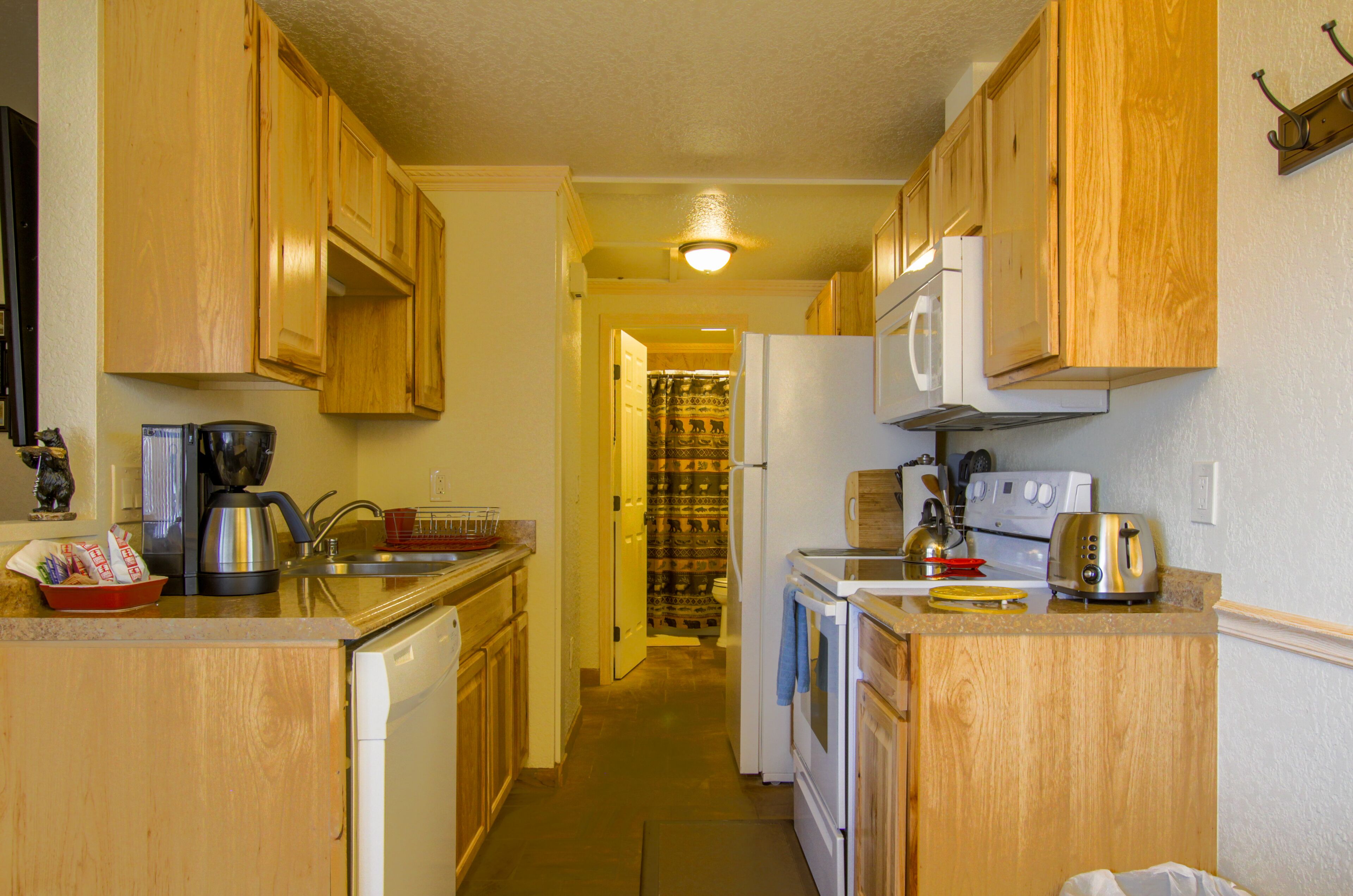 A narrow kitchen with wooden cabinets, a refrigerator, a microwave, and a toaster.