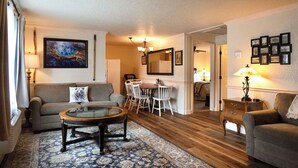 A living room with a sofa, a coffee table, a dining table with chairs, and a lamp. - Yellowstone Gateway Inn (Gardiner)