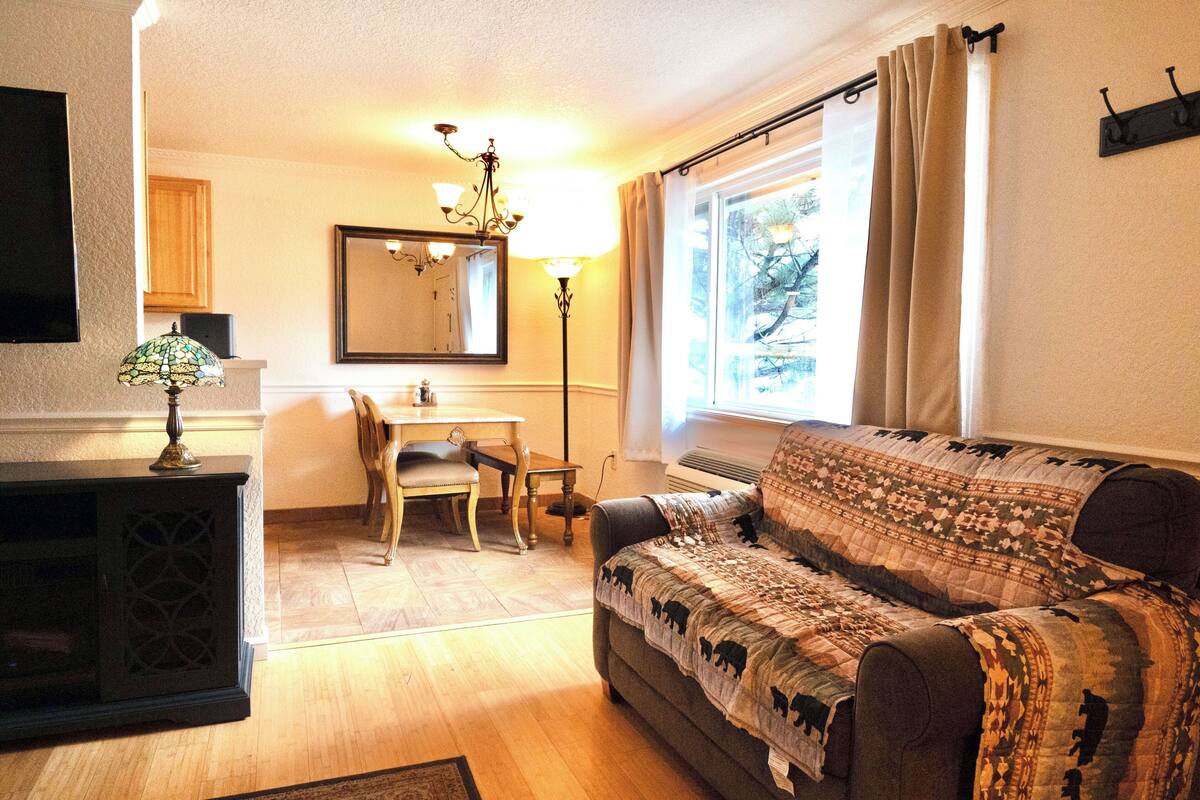 A cozy living room with a sofa, a dining table, and a TV.