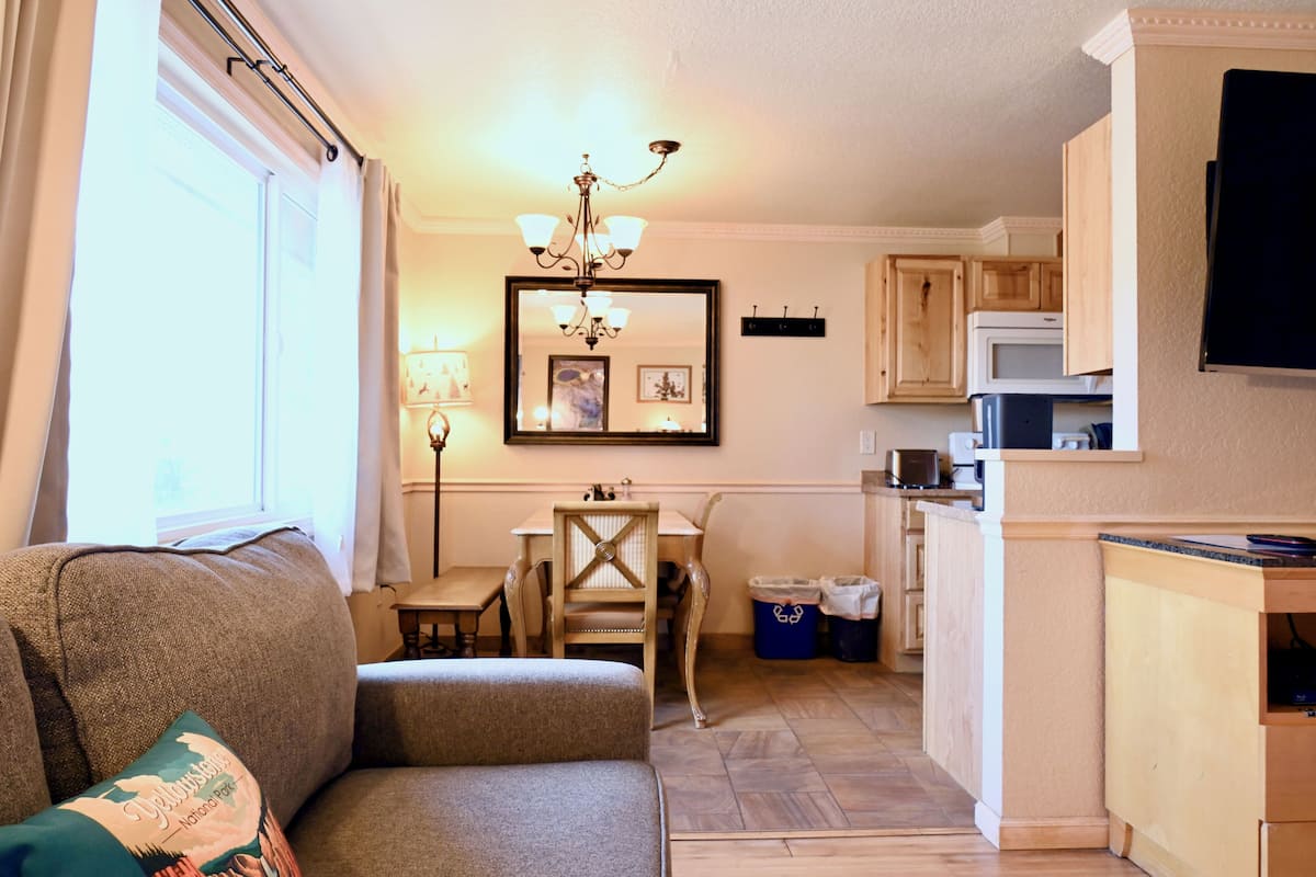 A compact living space with a sofa, a dining table, and a kitchen area including a microwave and cabinets.