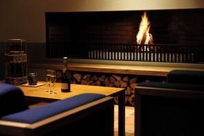 A cozy seating area with a fireplace, a bottle of wine, and glasses on a table.
