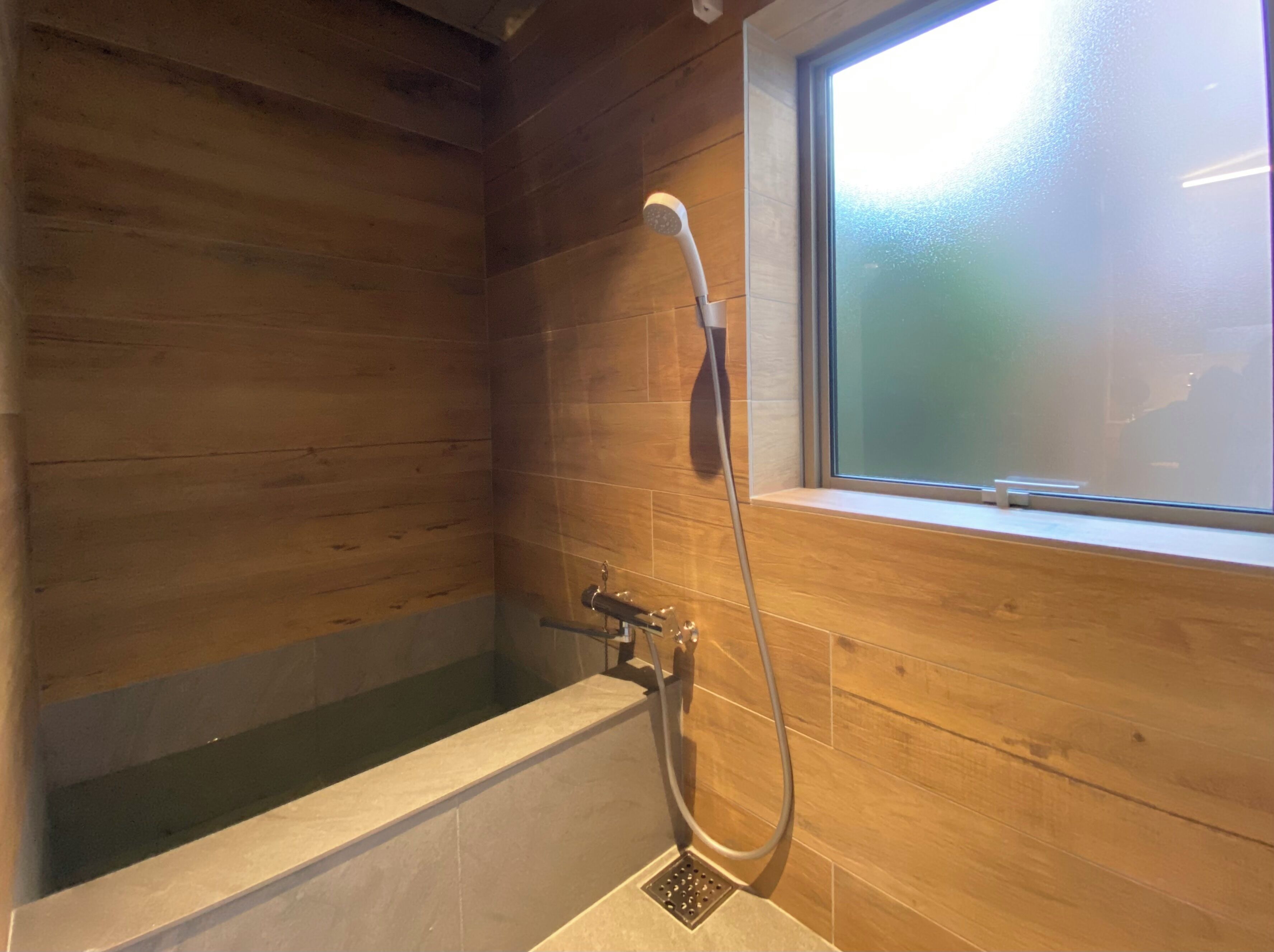 Un baño con paneles de madera, una bañera y un cabezal de ducha.
