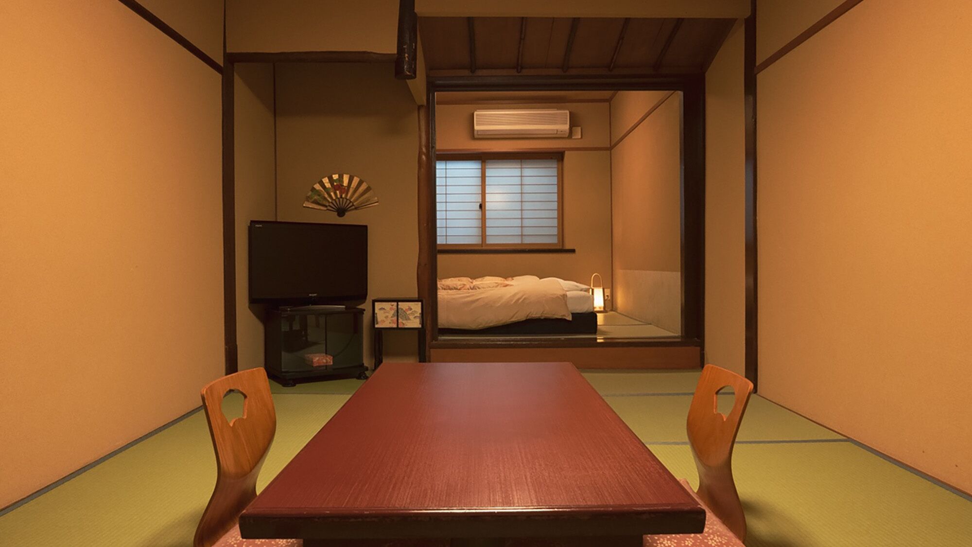 A traditional Japanese room with tatami flooring, a low table, and a futon bed.
