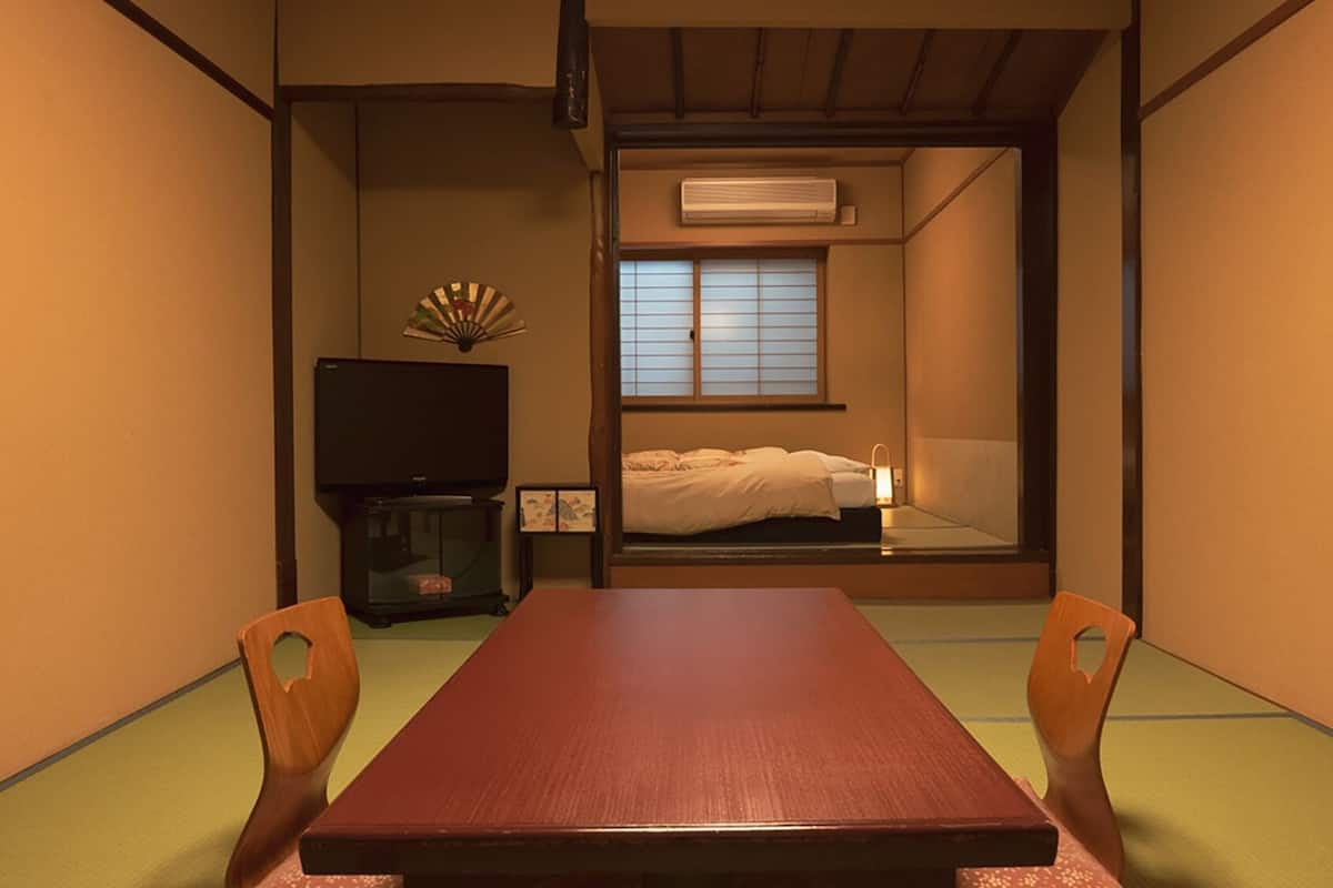 Um quarto japonês tradicional com tatames, uma mesa baixa e futon.