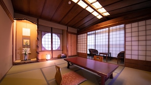 A traditional Japanese room with tatami flooring, a low table, and sliding doors. - Hokkaikan Ohanabo (Kyoto)