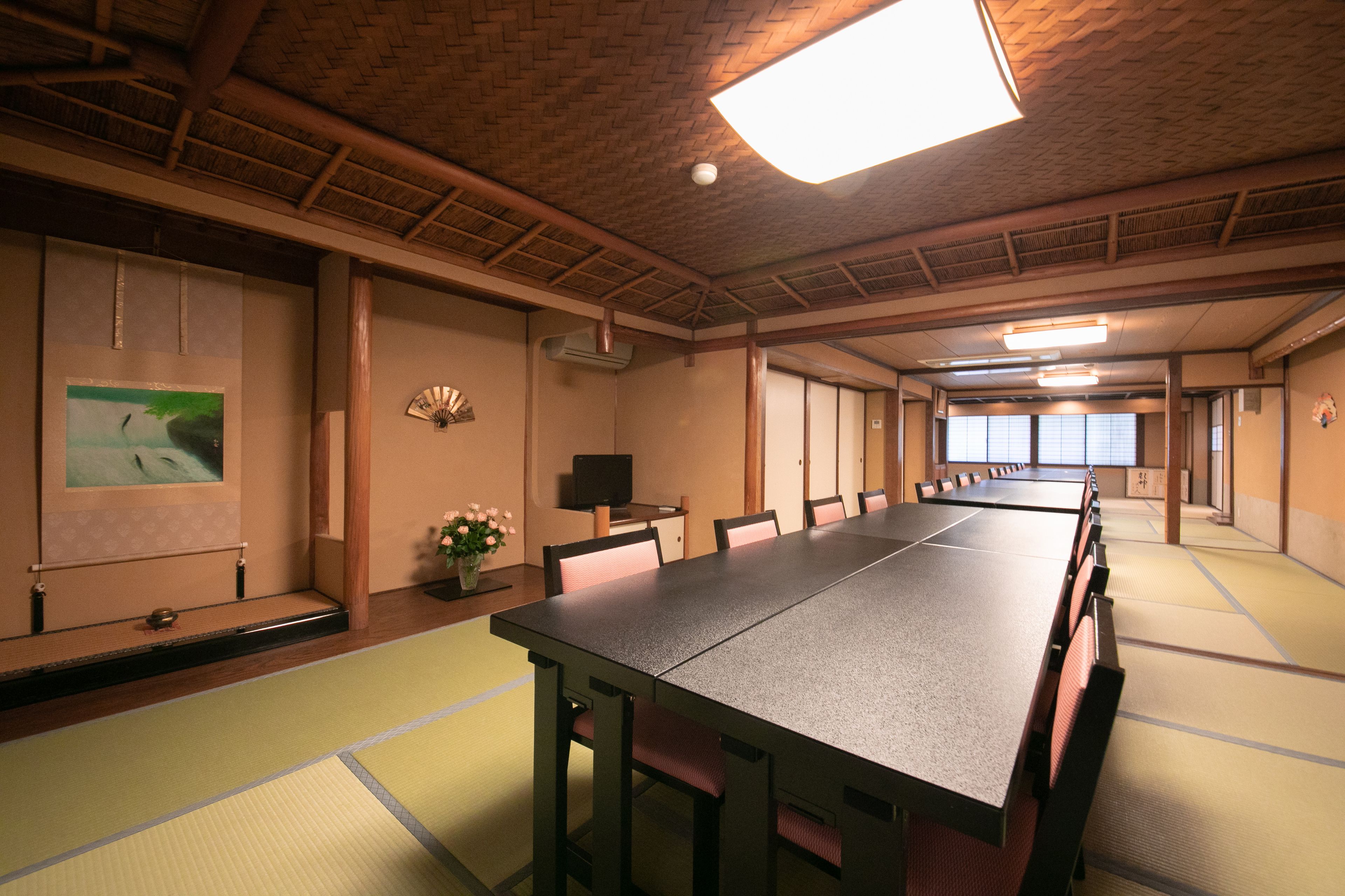 Una tipica stanza giapponese con pavimento in tatami, un tavolo lungo e paraventi shoji.