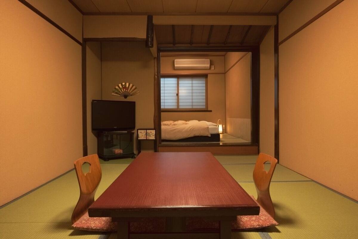 Una habitación tradicional japonesa con suelo de tatami, una mesa baja y sillas.