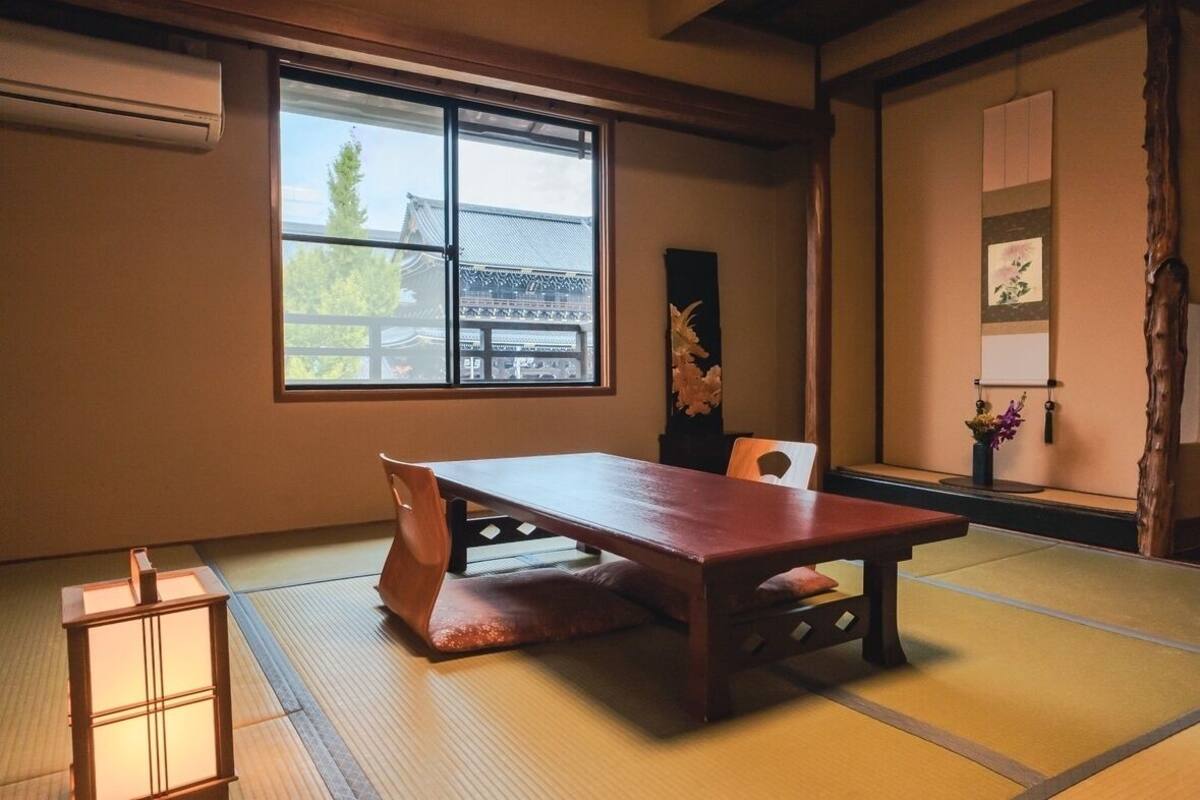 Una habitación japonesa tradicional con suelo de tatami, una mesa de madera baja y una puerta corredera con vistas a arquitectura tradicional.