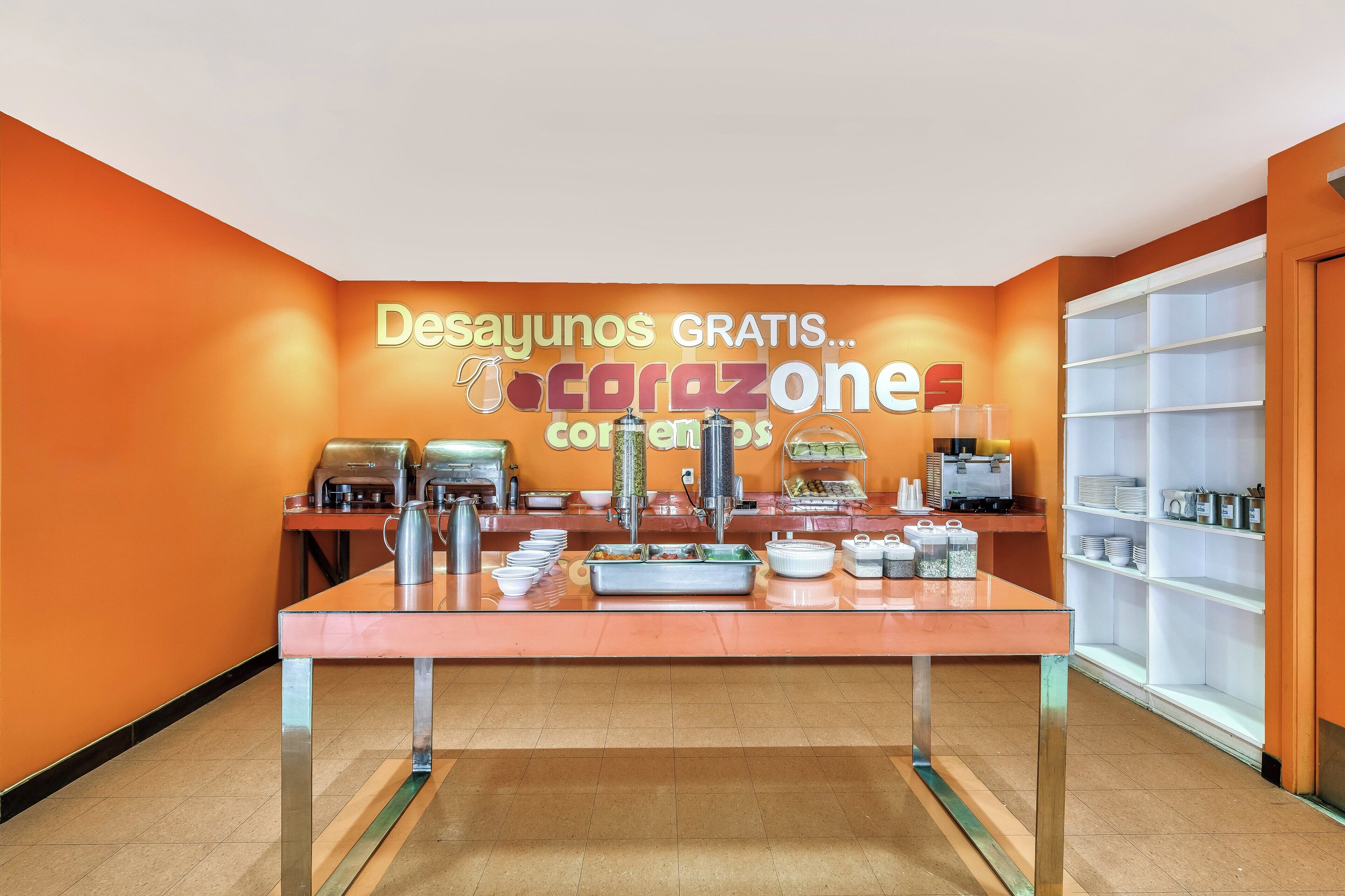 A buffet area with a sign offering free breakfasts, a coffee machine, and various food containers.