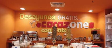 A breakfast buffet area with a sign indicating free breakfasts and a variety of food options.