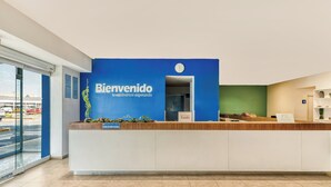 A reception desk with a blue sign that reads "Bienvenido te estamos esperando" and a clock above it. - One Salina Cruz (Salina Cruz)