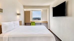A hotel room with a bed, a desk, a chair, a TV, and a window with a view. - One Salina Cruz (Salina Cruz)