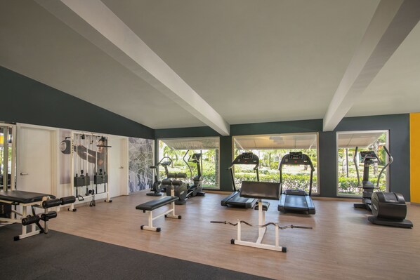 Un gimnasio con cintas de correr, elípticas y bancos de pesas.