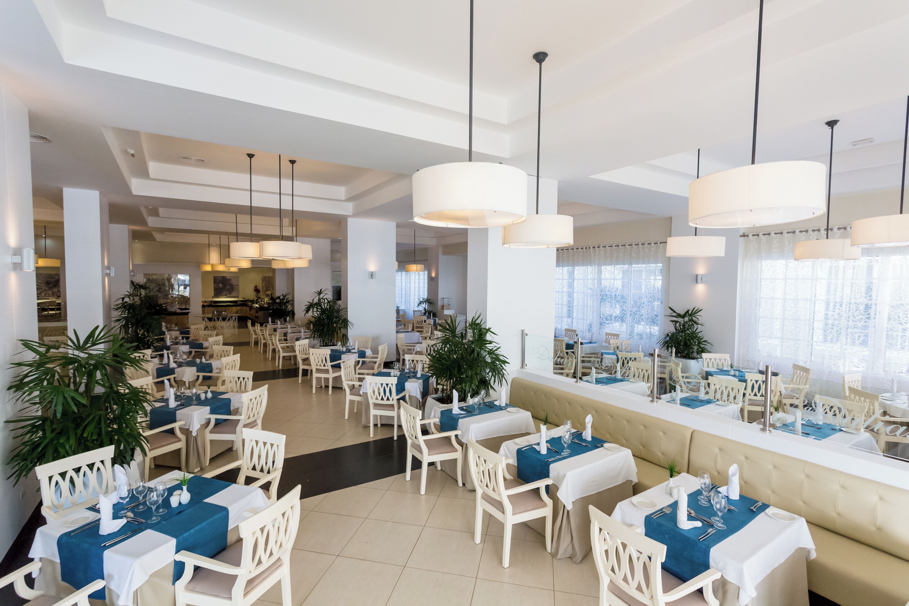 Een restaurant met witte stoelen, blauwe tafelkleden en hangende吊灯.