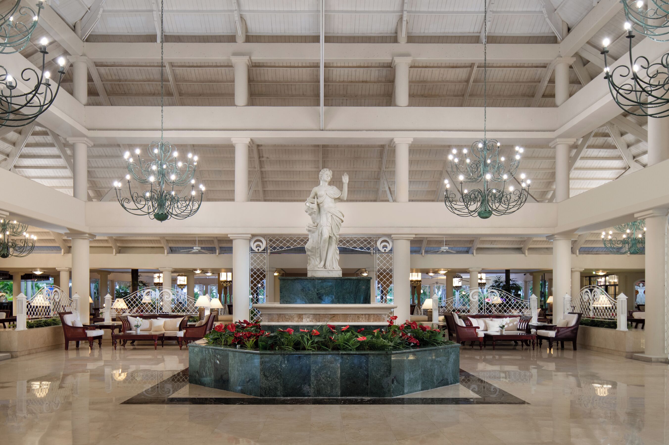 Un hall d’entrée spacieux, agrémenté d’une fontaine centrale, de coins salon et de lustres.