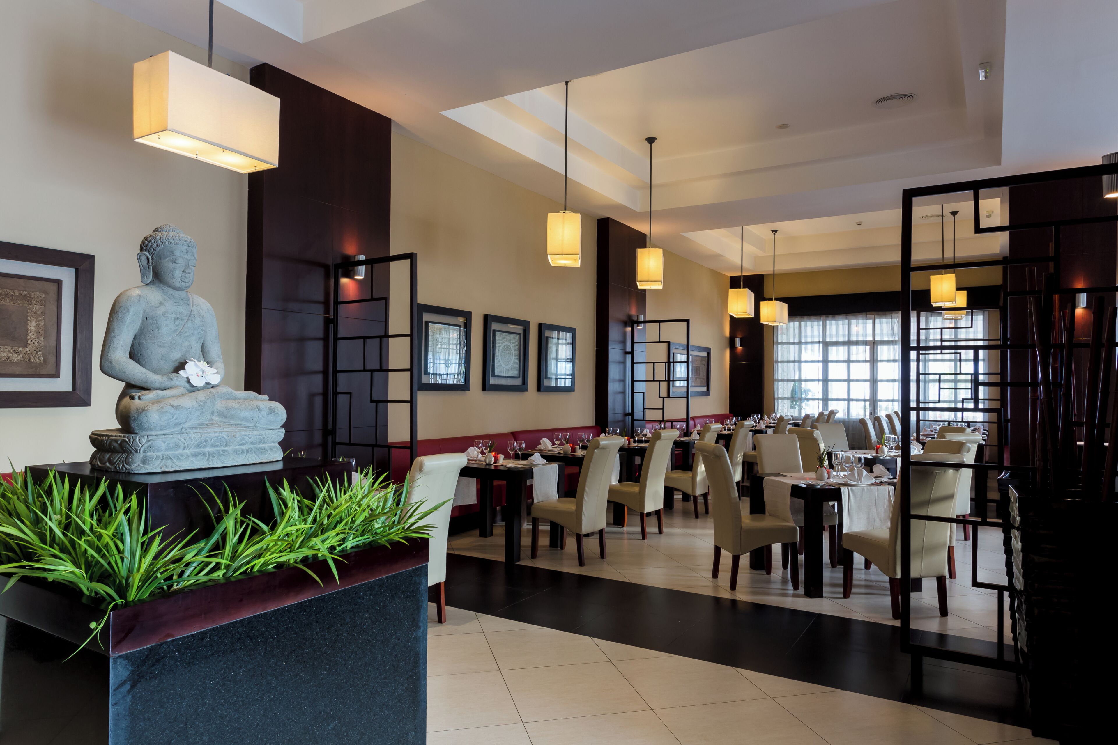 Ein Restaurant mit Buddha-Statue, gerahmten Bildern und Pendelleuchten.