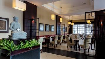 A restaurant with a Buddha statue, framed pictures, and pendant lighting.