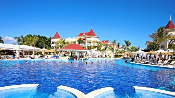 A large swimming pool with multiple levels of seating and a tropical architectural style.