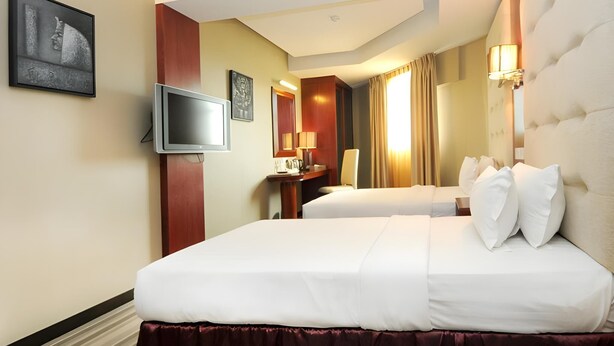 A hotel room with two beds, a TV, a desk, and a mirror.