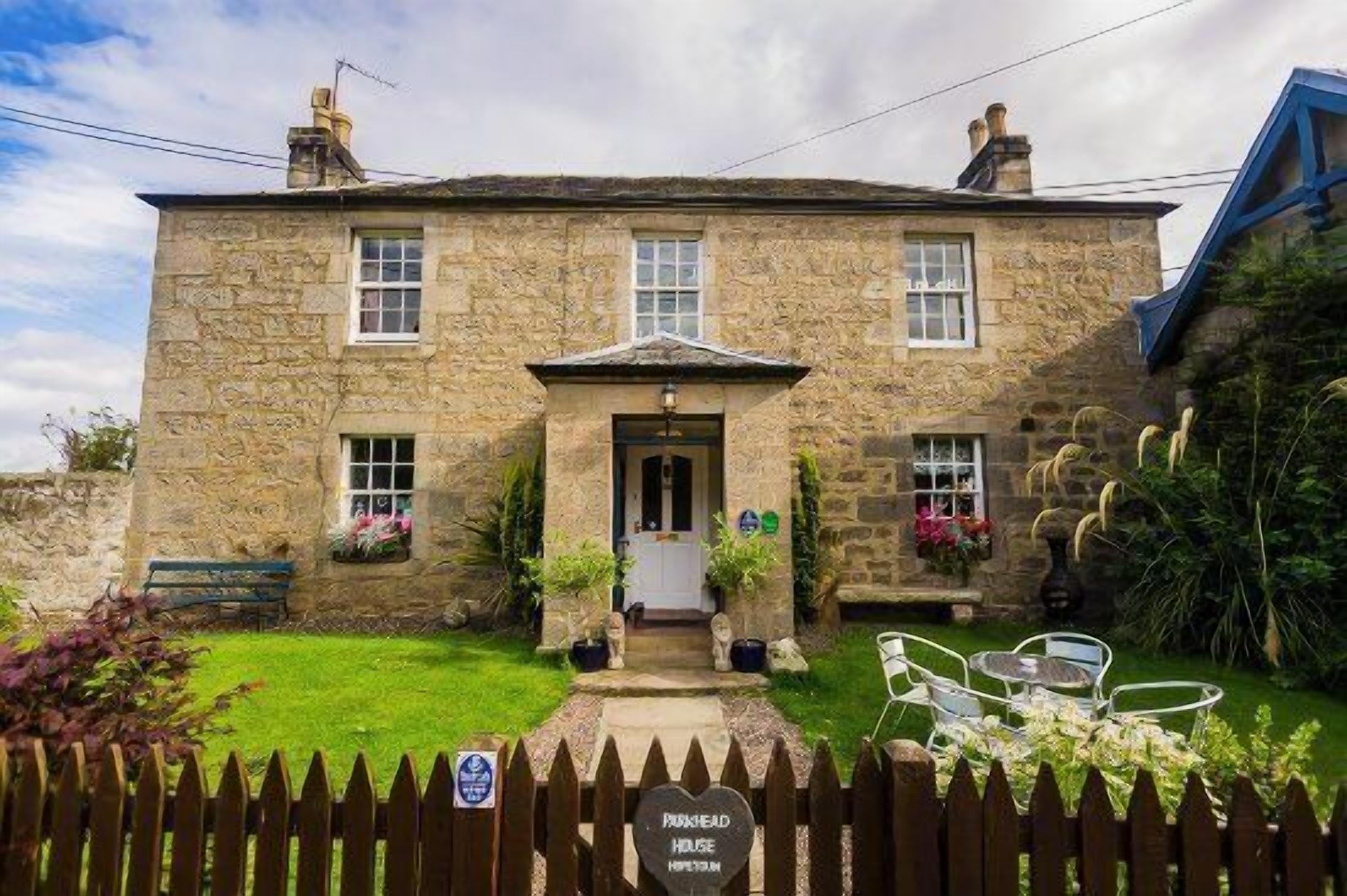 A stone building with a central entrance, a small porch, and a sign reading "Parkhead House."