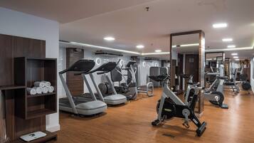 Un gimnasio con cintas de correr, elípticas y equipo de pesas.
