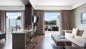 Een moderne hotelkamer met een bureau, bank en balkon met zitplaatsen.