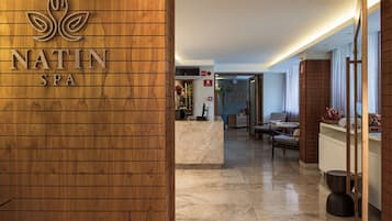 Un área de recepción con una pared de madera, un mostrador de recepción y un letrero que dice 'NATIN SPA'.