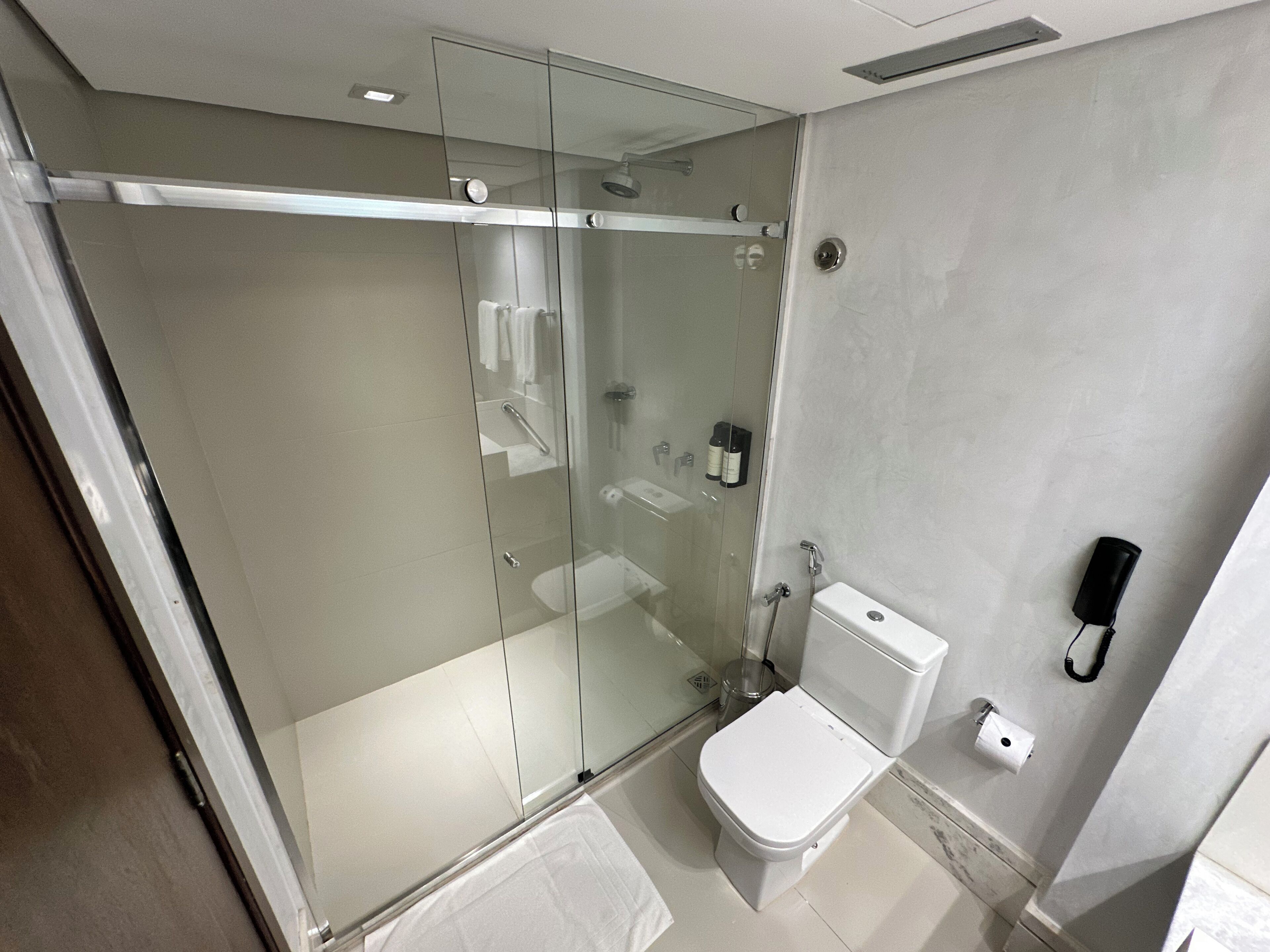 Un baño moderno con ducha de vidrio, inodoro y secamanos.