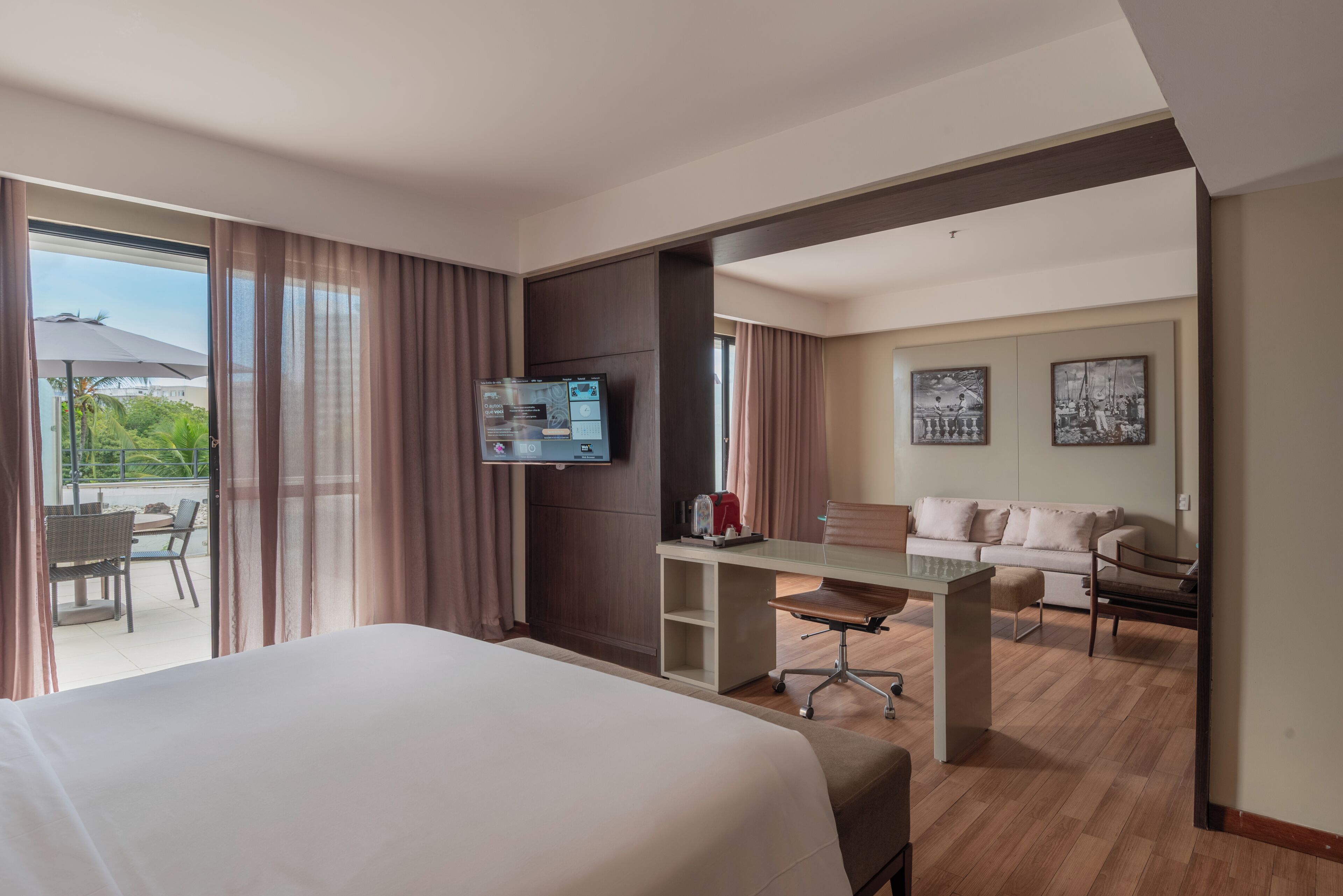 A hotel room with a bed, a desk, a sofa, and a television.