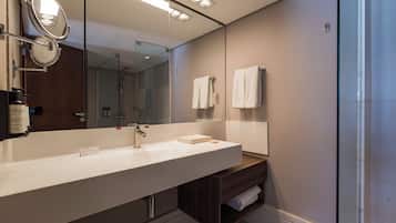 A modern bathroom with a large mirror, a white sink, and a glass shower enclosure.