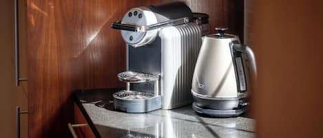 A compact kitchen with a coffee maker, a kettle, and a toaster on a countertop.