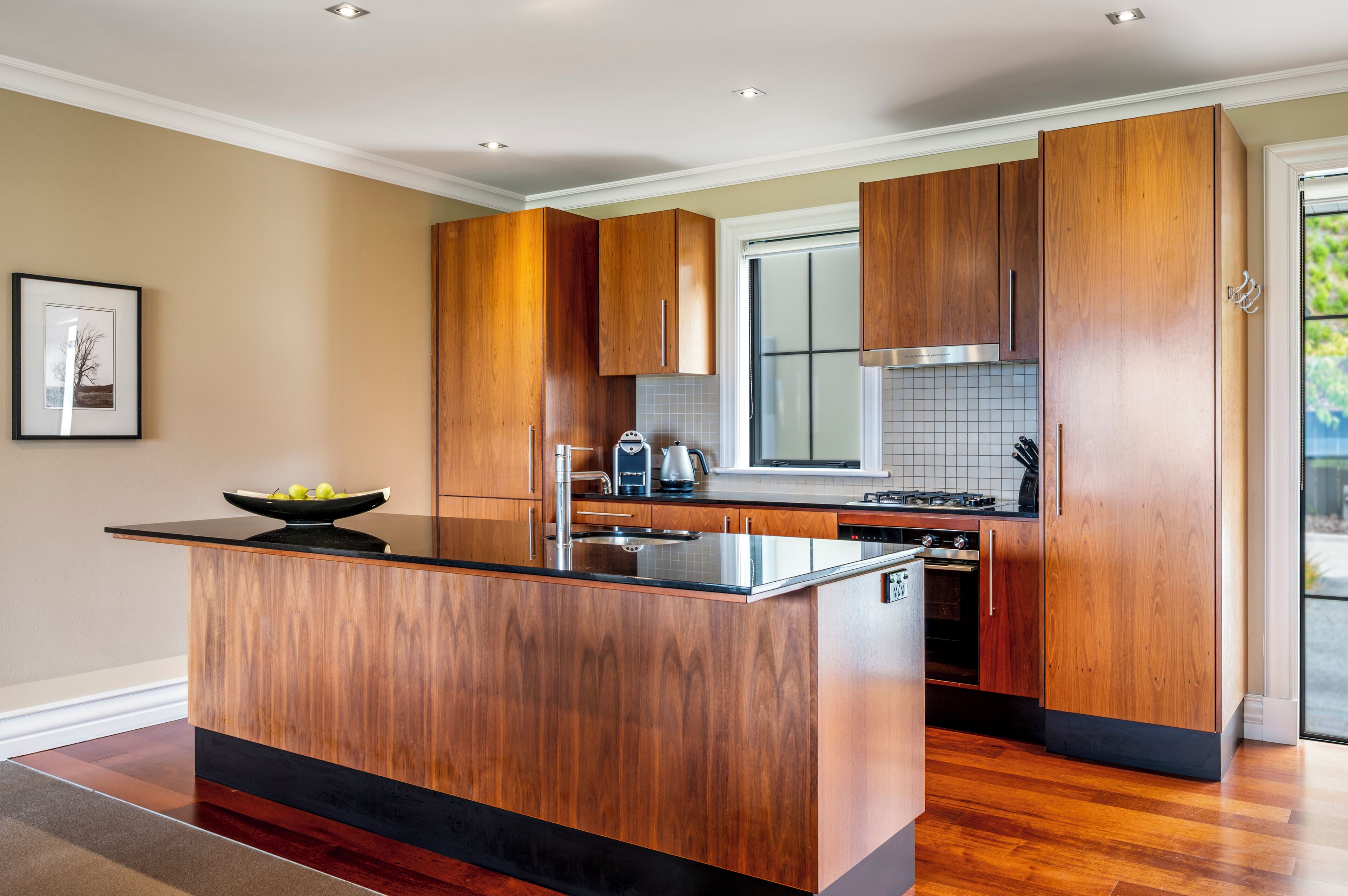 Une cuisine moderne avec des meubles en bois, un îlot central et un four encastré.