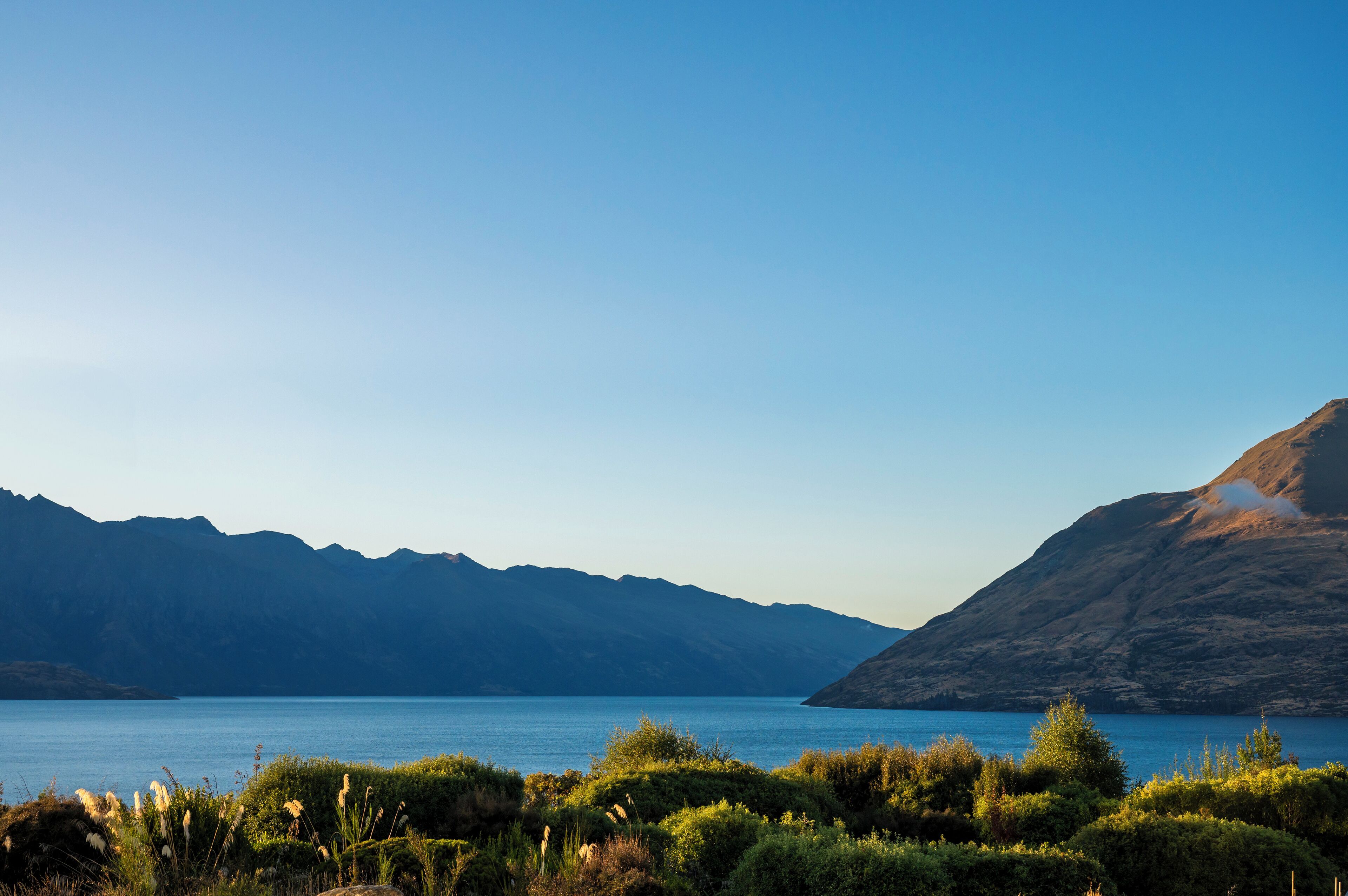 Un paysage montagneux, avec un ciel bleu dégagé et un lac paisible.