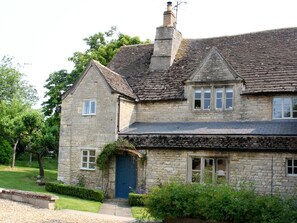 A stone house with a steeply pitched roof, a chimney, and a blue door. - Rectory Farm Annexe (Grantham)