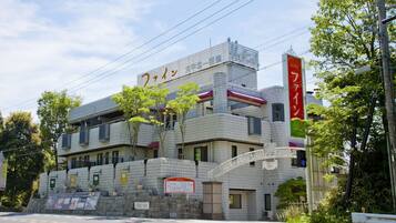 A hotel with a tiled facade, a signboard with Japanese characters, and a red banner.