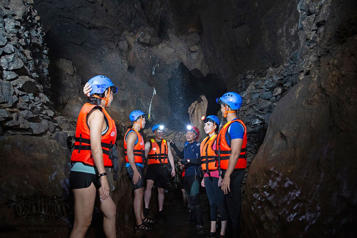 A group of people in a cave with rocky walls and a narrow passage.