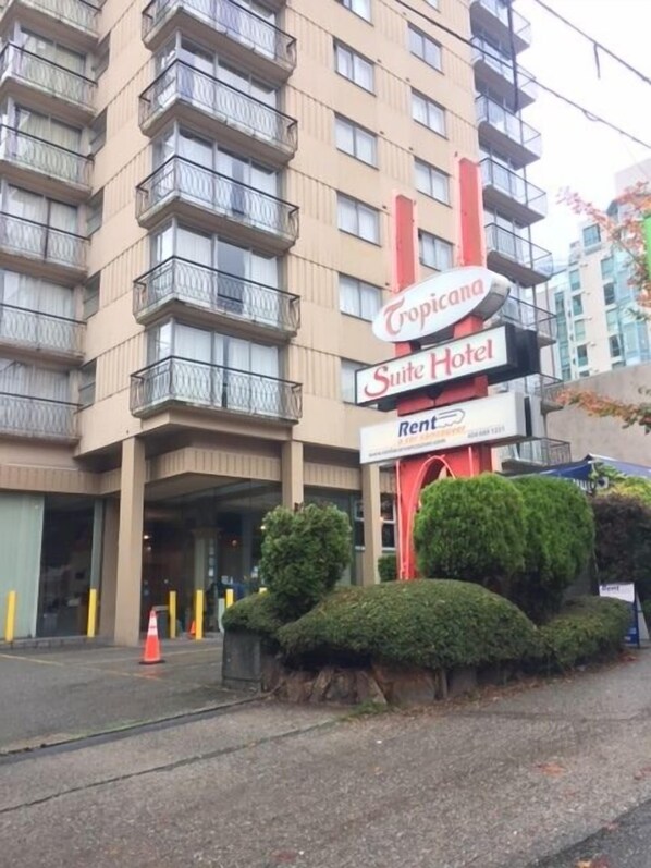 A multi-story hotel with balconies, a sign for Tropicana Suite Hotel, and a 'Rent' sign.