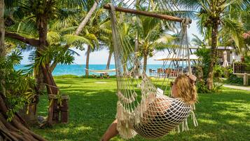 A hammock in a lush garden with a view of the ocean.