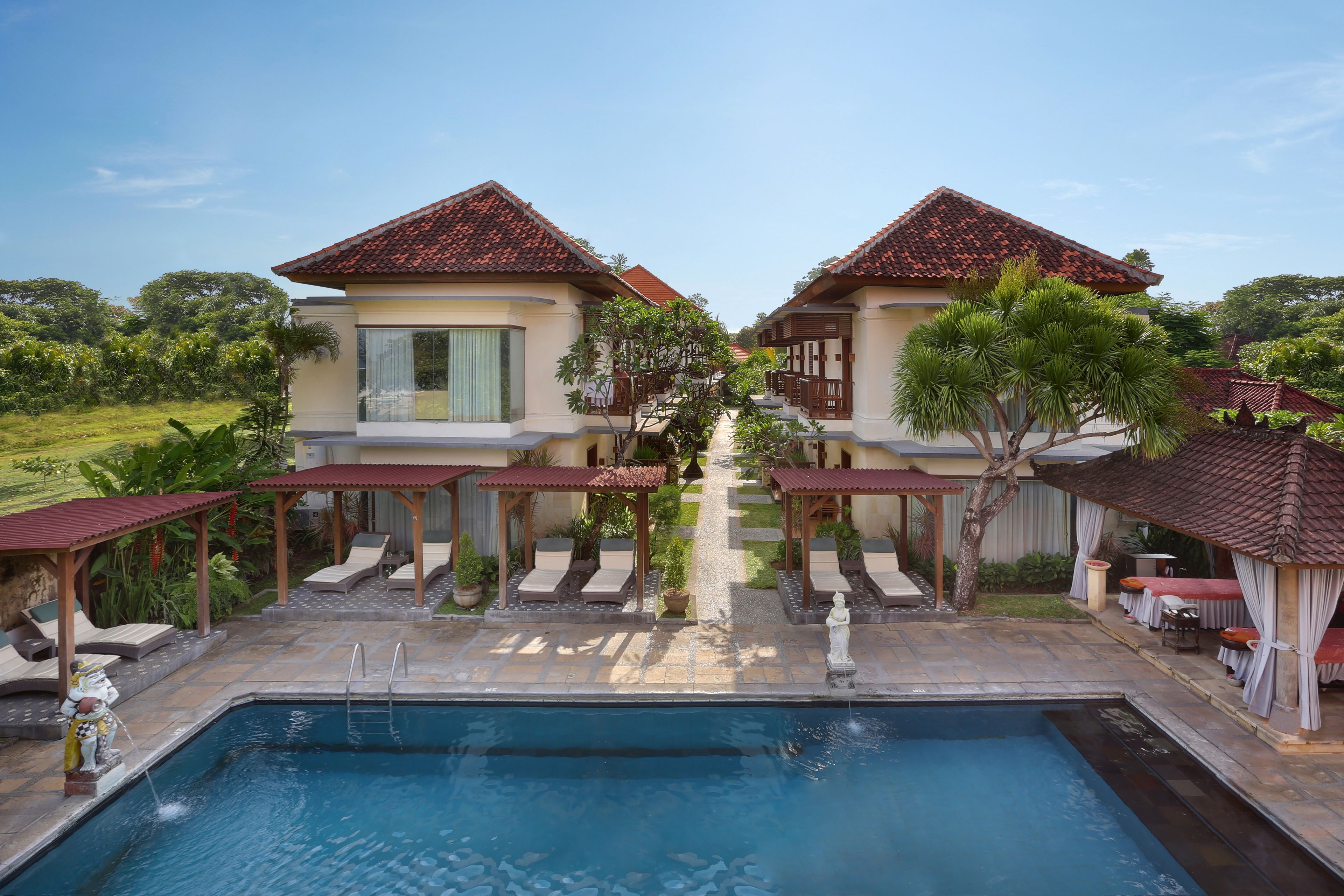 A pool area with two buildings, each with a tiled roof and a covered seating area.