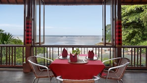 Comedor con mesa dispuesta para cuatro, con vista a la playa.