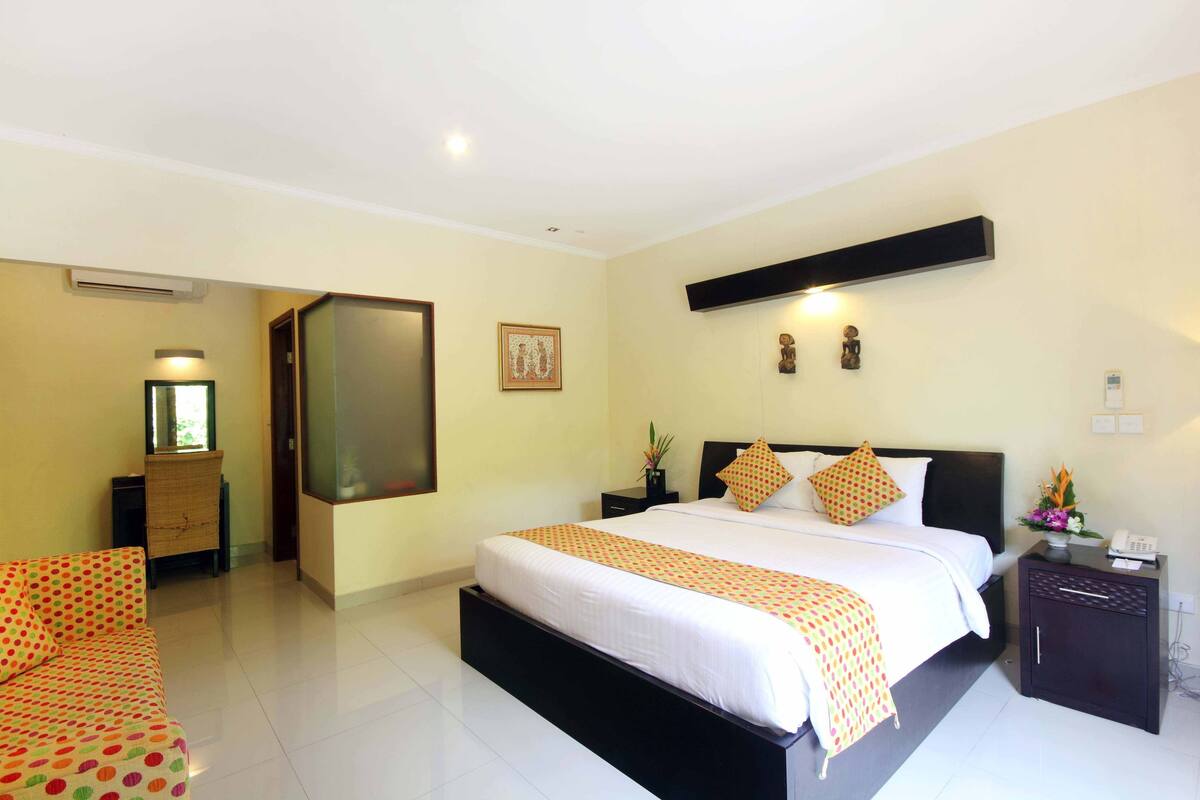 Une chambre d’hôtel avec un grand lit, une table de chevet avec un téléphone et une petite armoire.