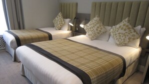 A hotel room with two beds, each with a headboard, pillows, and bedside lamps. - Garden Court Hotel (London)
