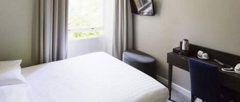 A hotel room with a large bed, a desk with a chair, a flat-screen TV, and a window with curtains.