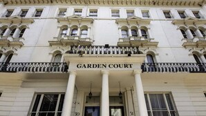 The facade of the Garden Court building with classical architecture, including columns and a balcony with black railings. - Garden Court Hotel (London)