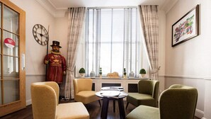 A room with a wooden floor, a round table with chairs, a statue, and a window with curtains. - Garden Court Hotel (London)
