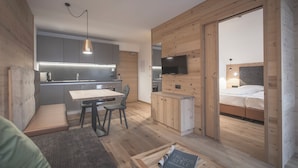 Un espacio habitable compacto con kitchenette, comedor, cama y televisor.