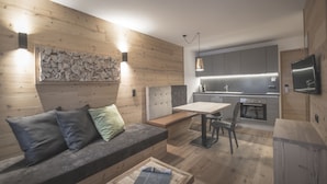Una cocina moderna con armarios de madera, un comedor con banco y un televisor integrado.