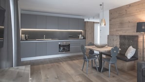 Una cocina moderna con armarios grises, una mesa de comedor de madera y un horno empotrado.