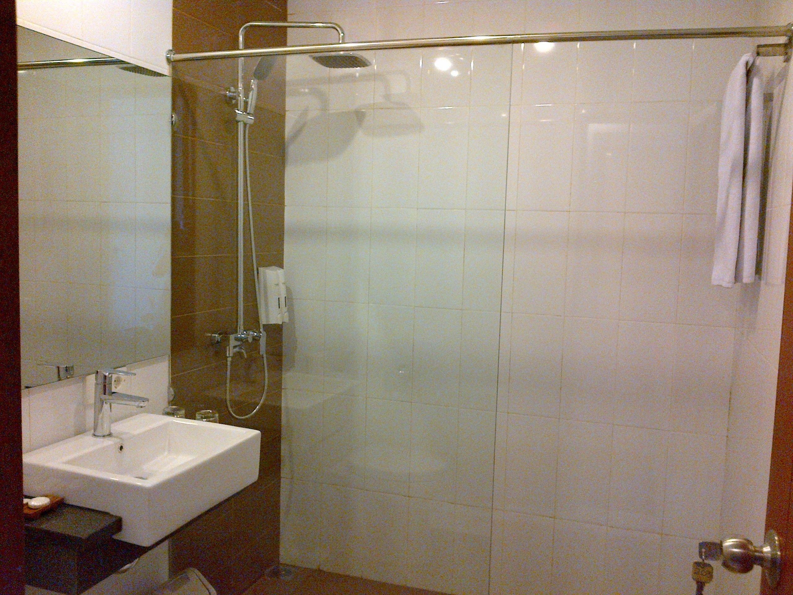 A bathroom with a glass shower enclosure, a sink, and a mirror.